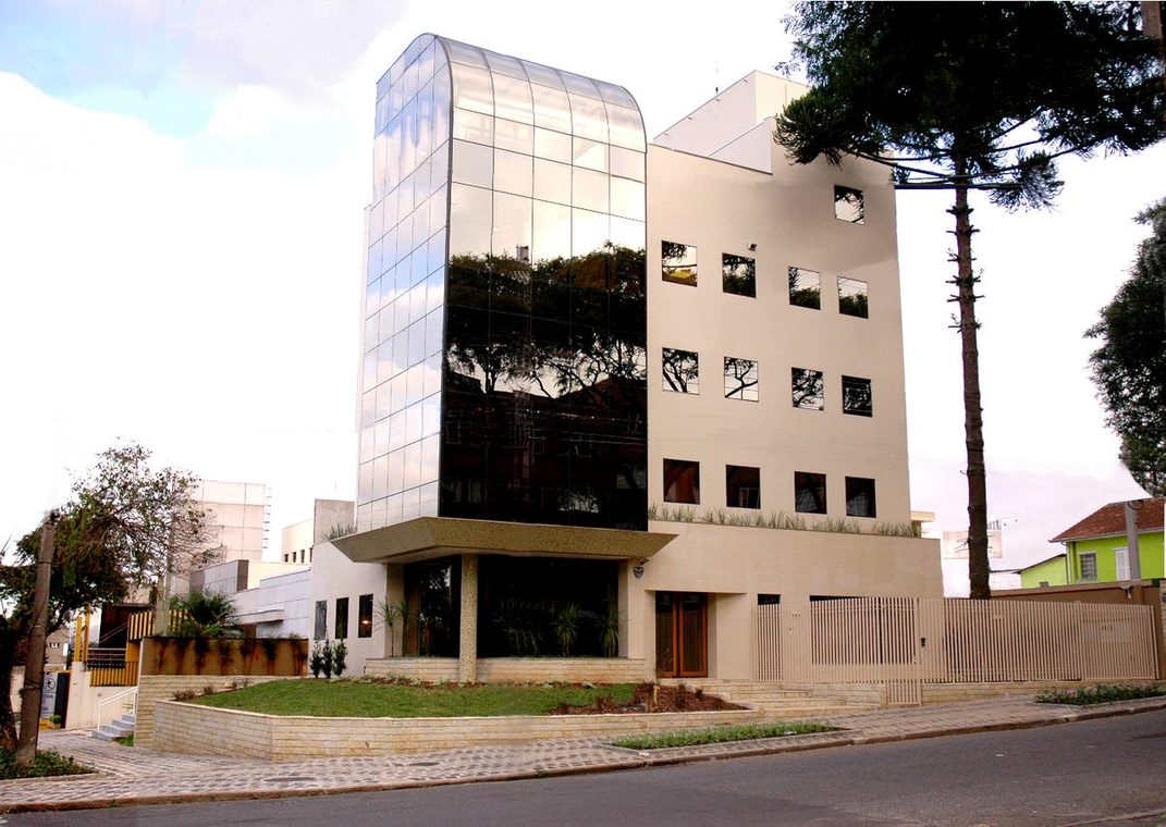 Edifício com torre de vidro e araucárias